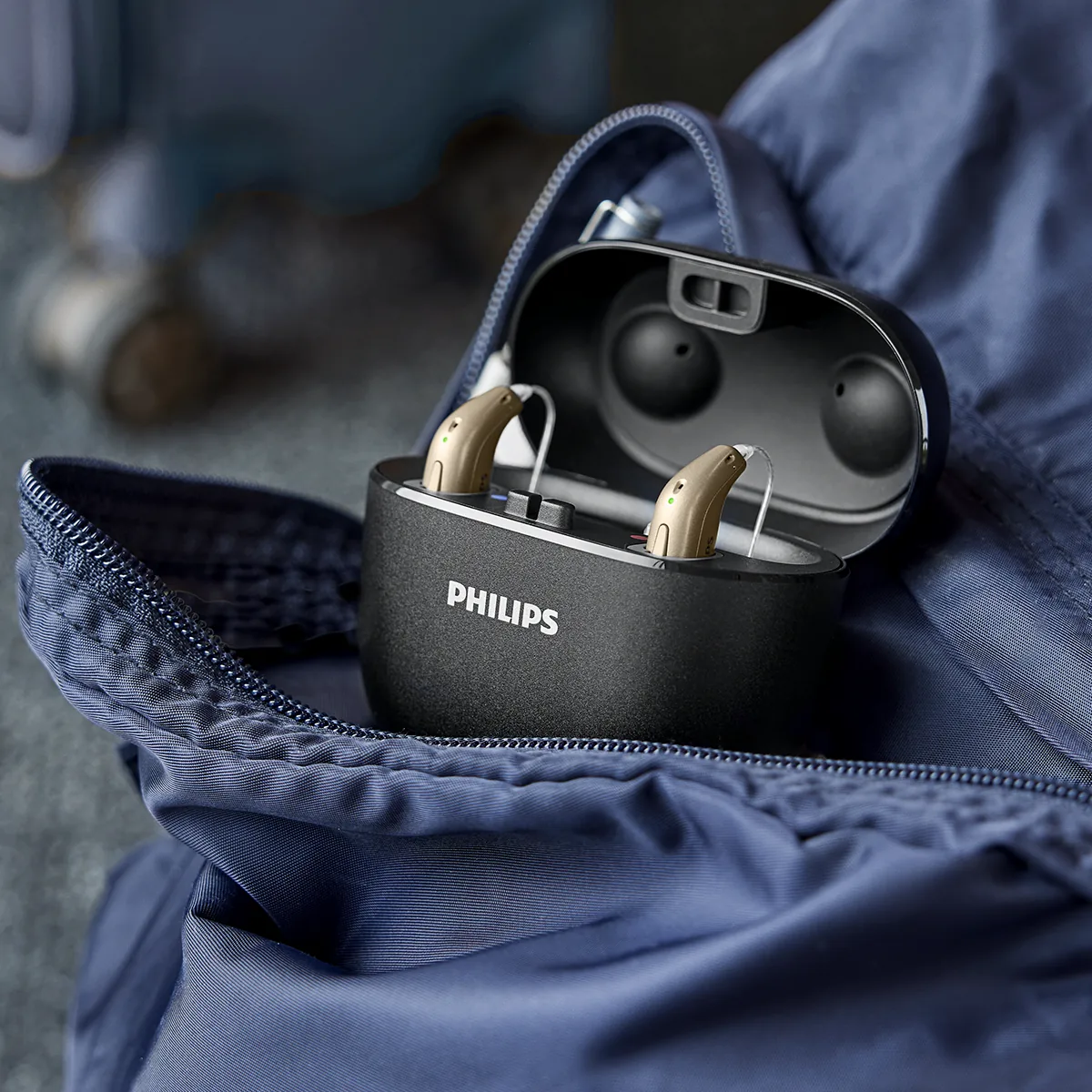 Philips HearLink 50 hearing aids in an open portable charger inside a bag